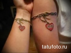 Фото парных татуировок сердец на запястьях. Красные и коричневые тона, символика любви и взаимосвязи, нежный дизайн.