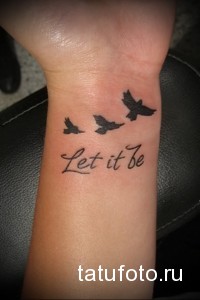 Фото тату на запястье с надписью 'Let it be' и тремя летящими птицами. Черно-белая татуировка, символизирующая принятие и свободу.