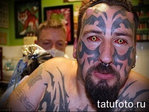 Фото мужчины с татуировкой в стиле трайбл, покрывающей большую часть его лица.