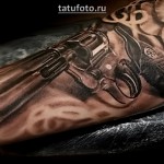 Реалистичная татуировка с револьвером на руке