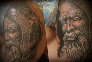 Фото тату: реалистичный портрет казака в шапке-ушанке с надписью на ленте. Детализированный рисунок татуировки на плече.