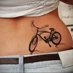 Татуировка с велосипедом на пояснице девушки