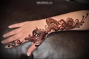 Фото мехенди на руке. Коричневый рисунок с узорами и цветочными мотивами, выполненный в традиционном стиле.