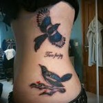 ворона в полете и надпись - женская татуировка на боку