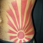 восходящее солнце в тату на боку у мужчины