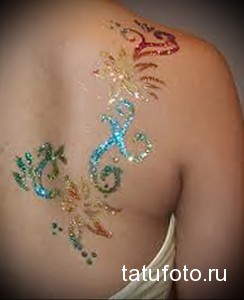 Фото блестящей татуировки на спине. Использование глиттера и ярких цветов создает эффектный образ.