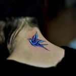 Фото тату яркой ласточки на шее. Татуировка выполнена в цвете с использованием синих, белых и черных оттенков.