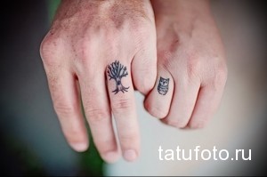 Фото парных татуировок на пальцах: на одном пальце изображено дерево, на другом - сова. Черно-белый рисунок, символизм природы.