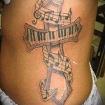 ерест из клавишей от пианино и ноты - женская татуировка на боку