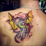 желто-красная татуировка с драконом на лопатке