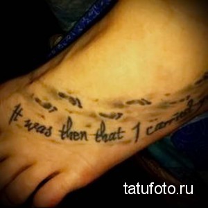 Фото тату на стопе с надписью 'It was then that I carried you' и маленькими отпечатками детских ножек, выполненными в черном цвете.