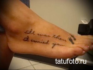 Фотография татуировки на стопе с надписью 'It was then I carried you', выполненной каллиграфическим шрифтом. Татуировка выполнена в коричневых тонах.
