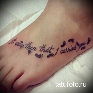 Фото тату на стопе с надписью 'It was then that I carried you' и маленькими отпечатками детских ножек, выполненными в черном цвете.
