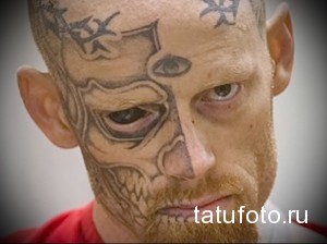 Фото тату: Мужчина с агрессивной татуировкой в стиле киберпанк на лице, изображающей глаз и механические элементы. Черно-серые тона.