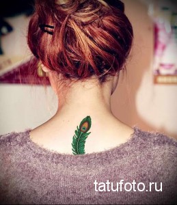 Фото тату: Красивое изображение пера павлина с яркими зелеными и синими оттенками, расположенное на затылке девушки. Детализированный рисунок татуировки.