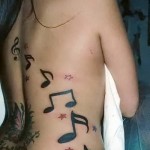 значки нот и звездочки - женская татуировка на боку