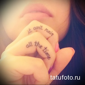 Фотография женского пальца с татуировкой надписью "It can't rain all the time". Минималистичная татуировка черным цветом.