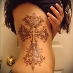 красиво сделанный крест - женская татуировка на боку