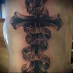 крест и даты на ленте в тату на боку у мужчины