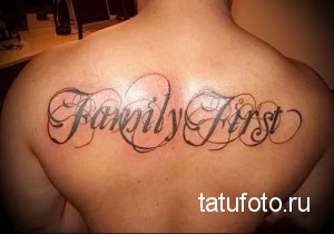 Фото тату на спине с надписью 'Family First'. Черно-коричневая татуировка в каллиграфическом стиле.