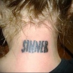 Фото тату на затылке: надпись "SINNER", выполненная в готическом стиле. Дерзкая и провокационная татуировка для смелых личностей.