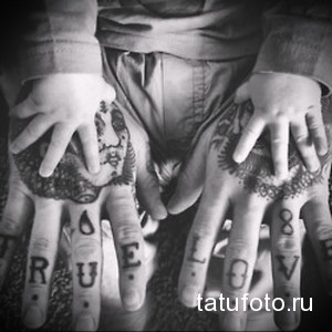 Фото тату с надписью 'TRUE LOVE', выполненной на фалангах пальцев. Черно-белый рисунок татуировки в минималистичном стиле.