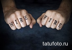 Фото татуировки с надписью "Hire Fire" на пальцах рук. Черный цвет, прямой шрифт, провокационный смысл.