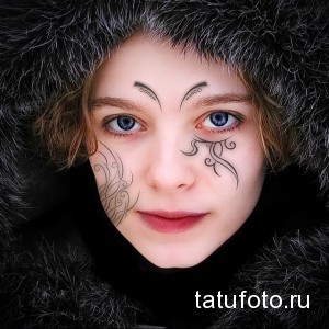 Фото тату на обличчі в стилі маорі. Чорні візерунки, симетричний дизайн, традиційні мотиви.