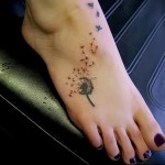 облетающие лепестки одуванчика и маленькие птички татуировка внизу ноги девушки