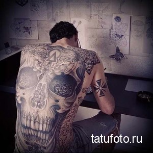 Фото тату: большая черно-серая татуировка с изображением сложного узора черепа и геометрических фигур на мужской спине.