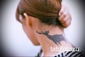 Фото тату: силуэт оленя с ветвистыми рогами, выполненный в технике blackwork на задней части шеи. Минималистичный рисунок татуировки.