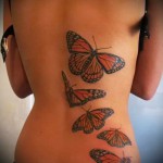 оранжевые бабочки в полете тату на спине женская