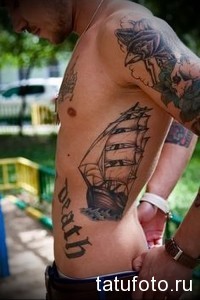 Фото тату корабля на боку мужчины с надписью 'death'. Черно-серый рисунок, морская тематика, детализированный эскиз татуировки.