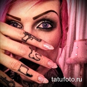 Фото тату на пальцах: пистолет, череп и нож. Смелый и дерзкий рисунок татуировки, выполненный в черном цвете.