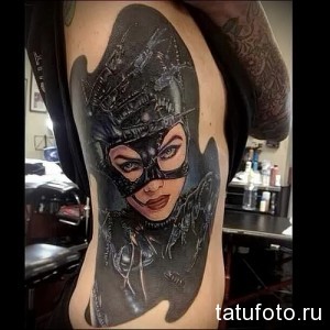 Фото тату Женщины-кошки на боку. Реалистичный портрет героини комиксов с маской и костюмом. Выполнено в ярких цветах с использованием теней и бликов.