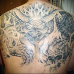 рогатый демон в аду и черепа - тату мужская на спине фото