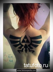 Фото тату в стиле Zelda на спине. Черно-белый рисунок с изображением крыльев и символа трифорс. Символ свободы и приключений.