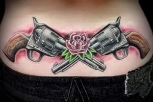 Фото тату: Два скрещенных револьвера и роза на женском животе. Цветной рисунок татуировки.