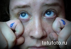 Фотография татуировок в виде голубых слез под глазами на пальцах рук. Минималистичный стиль, яркий цвет.