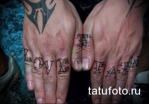 Фото татуировки с надписью "Love Hate" на пальцах рук. Готический шрифт, контраст, символ двойственности.