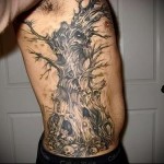 страшное дерево с черепами в тату на боку у мужчины