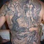Фото тату на спине: воин-ангел с мечом, стоящий на фоне дерева и сражающийся с драконом, выполненное в реалистичном стиле с использованием серых оттенков.