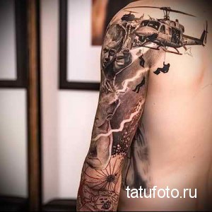 Фото тату: реалистичная татуировка с изображением вертолета, солдата и пейзажа, выполненная на плече.