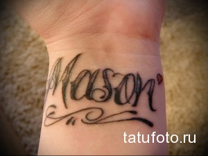 Фото тату на запястье: Имя 'Mason' выполнено каллиграфическим шрифтом с декоративными элементами, создавая элегантный и персонализированный дизайн.