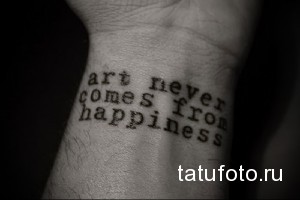 Фото тату на запястье: Надпись 'art never comes from happiness' выполнена стилизованным шрифтом, создавая философский и вдохновляющий дизайн.