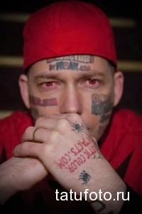 Фото тату на лице мужчины: надписи, символы и рисунки, покрывающие большую часть лица. Экстремальный стиль татуировки.