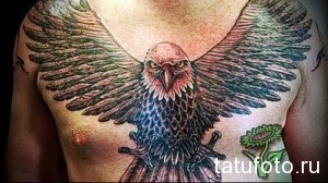 Фото тату орла с кинжалами на груди мужчины. Яркий рисунок с использованием различных цветов и деталей.
