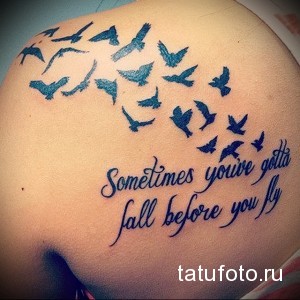 Фото татуировки на спине с изображением стаи летящих птиц и надписью "Sometimes you've gotta fall before you fly". Символизирует преодоление трудностей и стремление к свободе.
