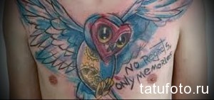 Фото акварельной татуировки на груди с изображением совы и надписью 'No regrets, only memories'. Мягкие переходы цветов и размытые контуры.