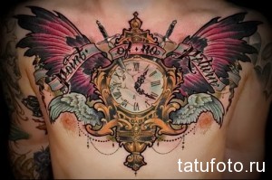 Фото тату: красочные часы с крыльями и надписью 'Time of no return' на груди мужчины. Детализированный рисунок татуировки в стиле реализм.